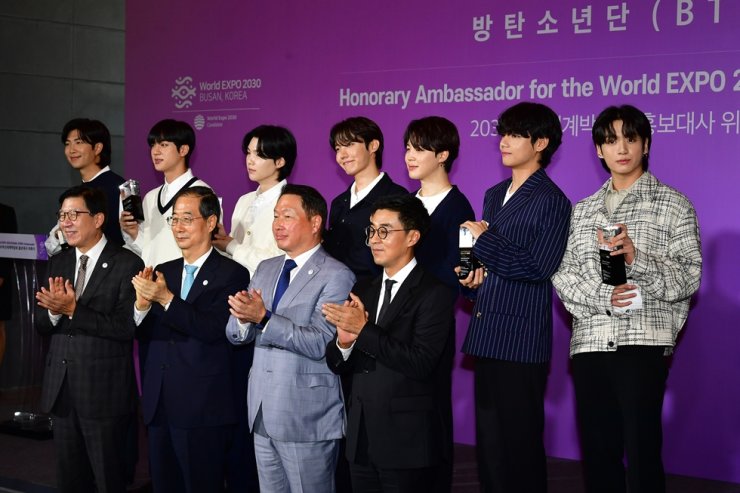 In this July 19, 2022 file photo, members of K-pop group BTS, in the back row, Prime Minister Han Duck-soo, front row second from left, pose during a ceremony appointing the BTS members as honorary ambassadors for the World Expo 2030 at HYBE's office in Yongsan, Seoul. Korea Times file